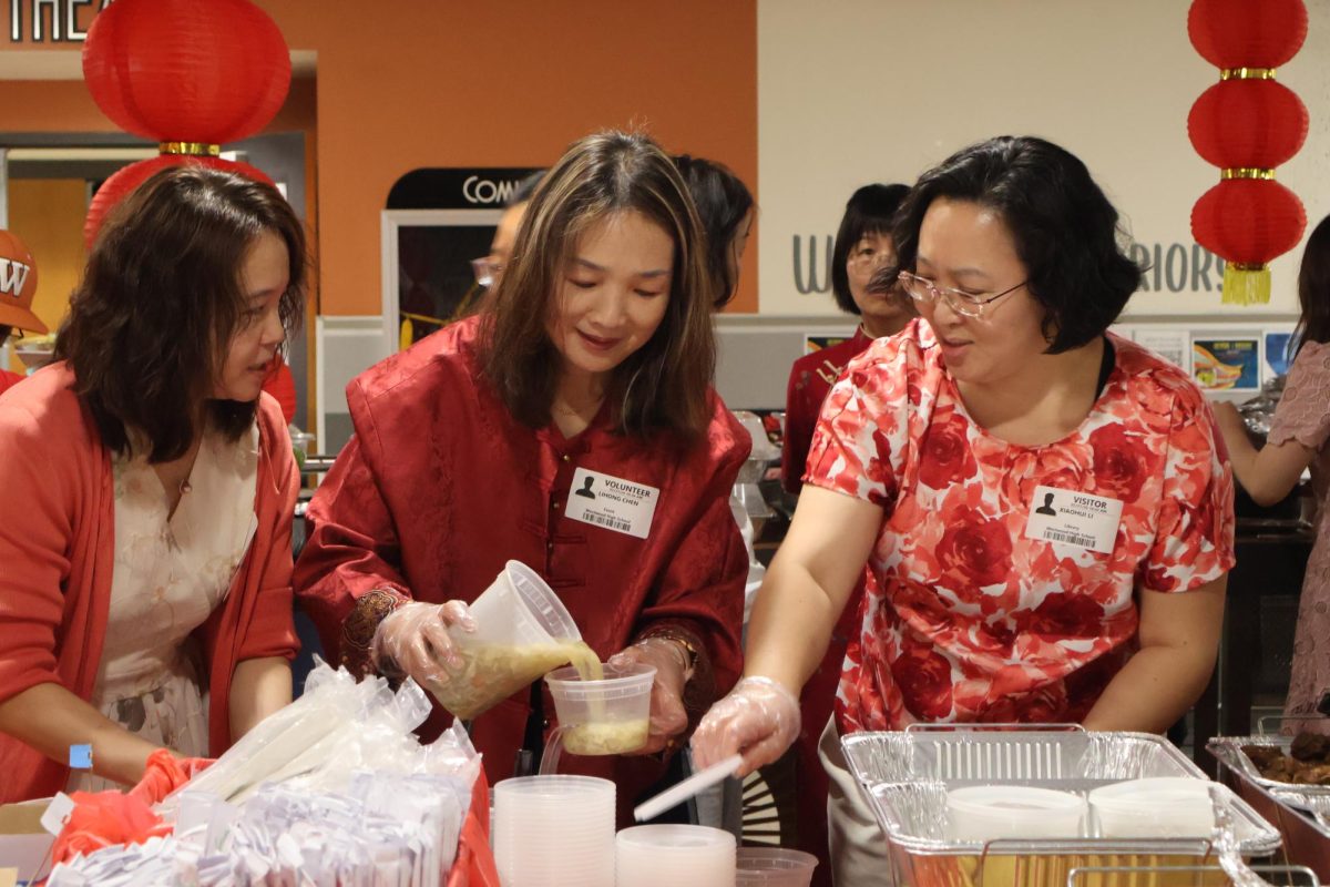 Smiling, parent volunteer Lihong Chen pours egg drop soup into a small container for a teacher grabbing lunch. Chen was an active member during the event, setting up the dishes well before the faculty started trickling in. 