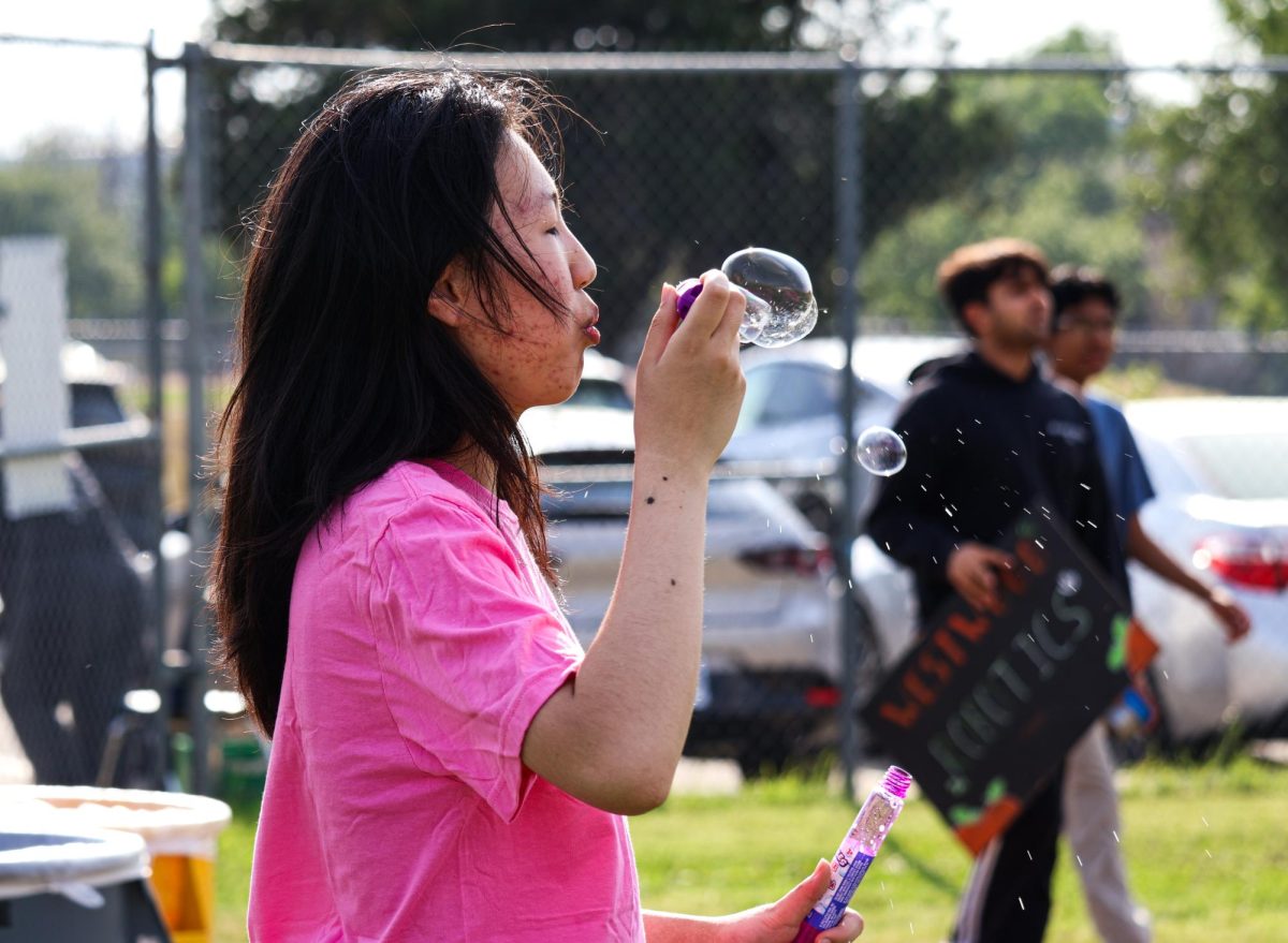While waiting for booth visitors, Xinyi Lai ‘26 entertains incoming WarriorFest attendees by blowing bubbles. Organized by National Honor Society (NHS) members, WarriorFest proceeds are used to support the Thirst Project, a nonprofit that aims to provide freshwater wells to developing communities.