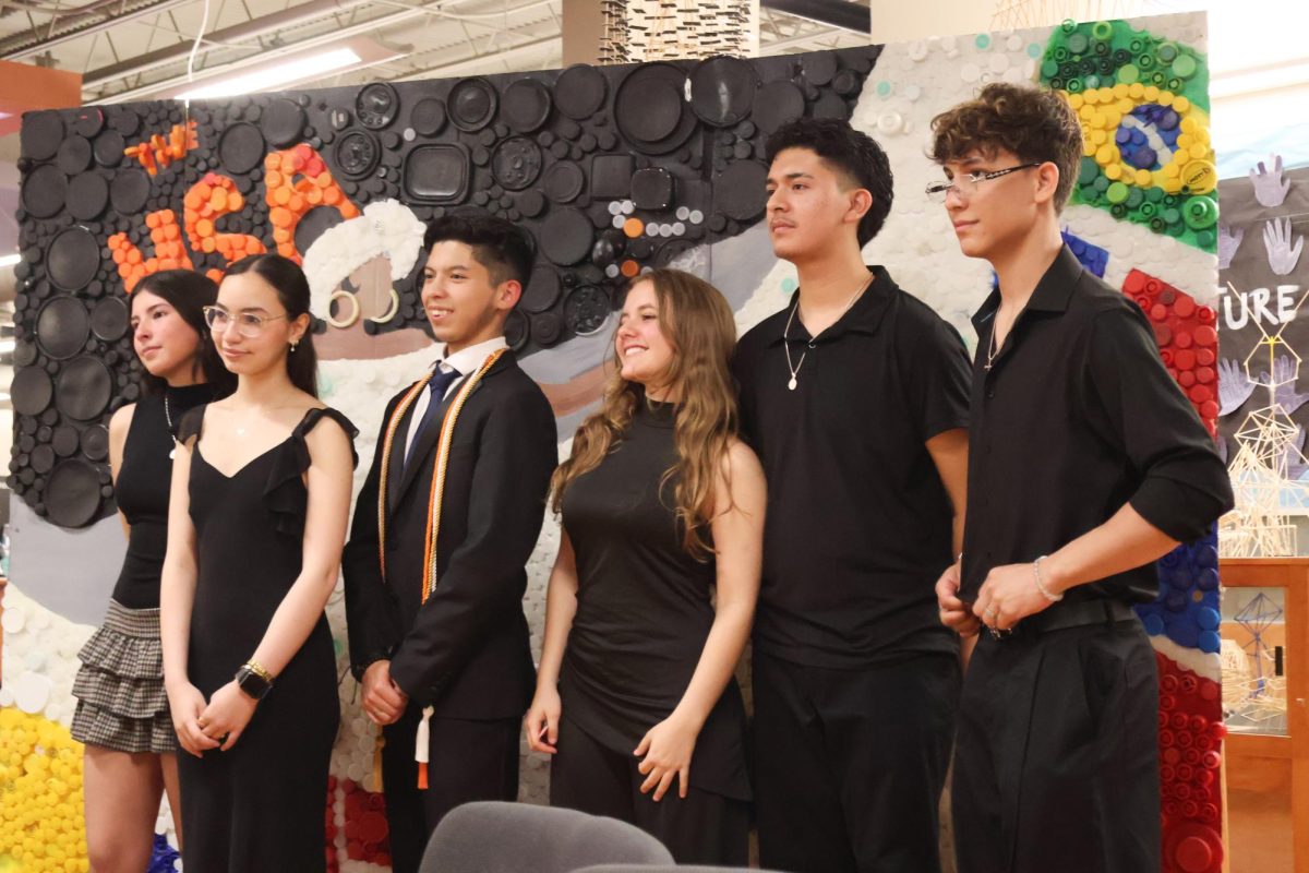 Dressed their best, officers Zarah Wetter '28, María Rodriguez '26, Mainor Josue Lainez '26, Maria Rincon '27, Alan Castillo '27, and Miguel Torres Jaramillo '28 stand behind their crafted mural "Rhythms of Latin America" for a group picture. Since its creation in the previous year, the mural served as a physical symbol of cultural inclusivity through recycling.