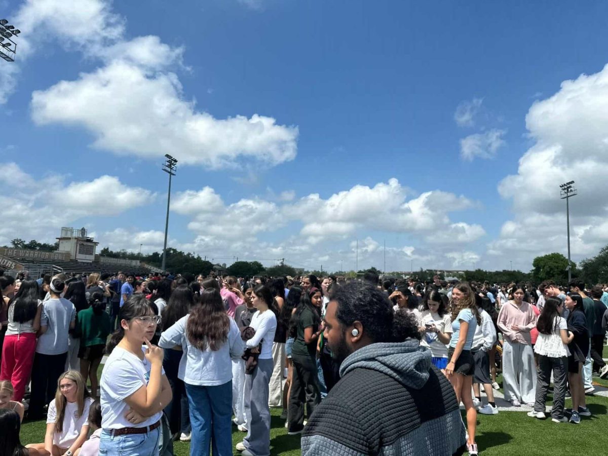 Confused, students and staff gather in the Warrior Bowl following a sudden evacuation during third block. As the temperature rose to 82 degrees Fahrenheit, students found out that the evacuation was caused by a bomb hoax, speculated by officials to be part of a larger series of swatting incidents.