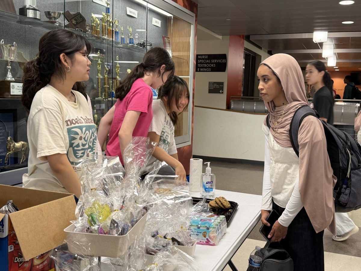 Listening to Erin Shin '28, Dalia Ahmed '28 pays close attention to the K-Pop Club Bake Sale. Along with assorted sweets, the club offered blind boxes for sale as well, adding a layer of intrigue that helped them stand out among other fundraisers.