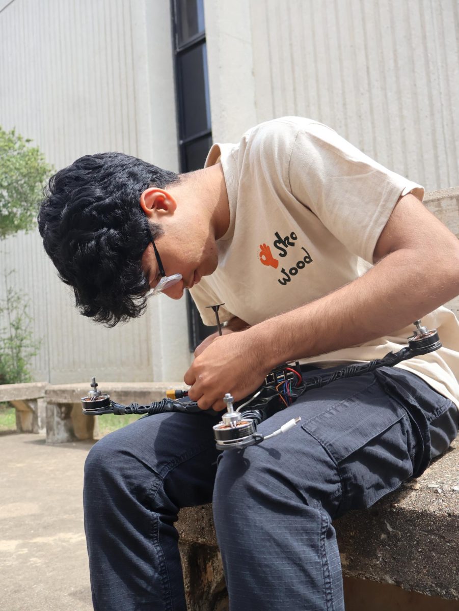 Carefully inspecting the drone's wiring and components, Sol Mahajan ’26 examines his ISEF project. The project, built over months of testing and iteration, reflects his focus on engineering design and problem-solving beyond what’s visible in the moment.