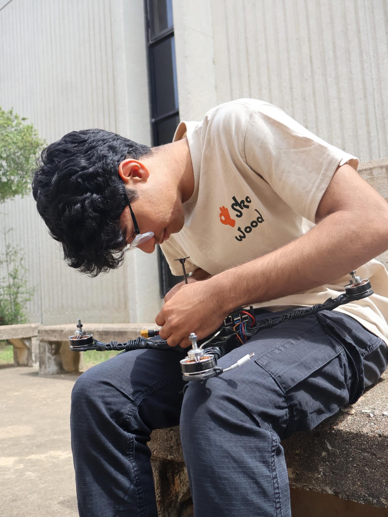 Carefully inspecting the drone's wiring and components, Sol Mahajan ’26 examines his ISEF project. The project, built over months of testing and iteration, reflects his focus on engineering design and problem-solving beyond what’s visible in the moment.