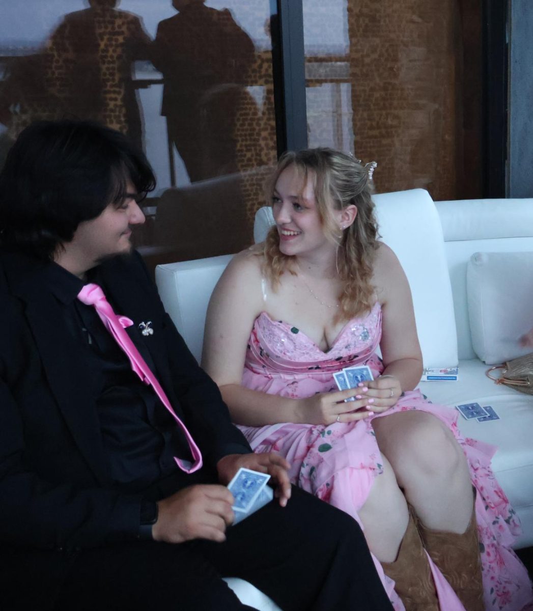 Holding cards, Molly Burnside '26 passes time while waiting for friends to arrive at prom. While games were available for dancers, some opted to bring their personal games.