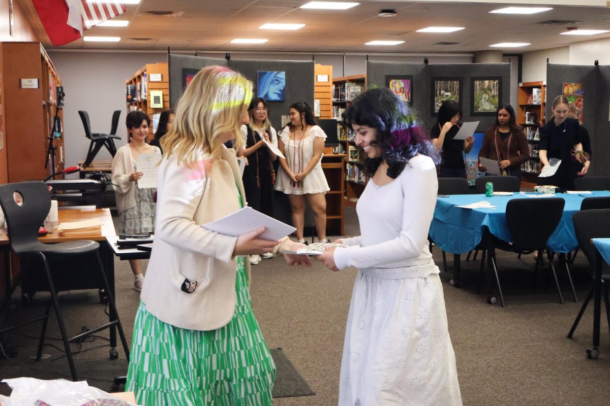 Smiling warmly, NAHS Sponsor Elizabeth Gross hands Sahana Suryanarayan '26 her certificate of accomplishment. Speaking through the microphone, Mr. Jesus Ramirez called the names of each senior member to the front of the Great Room to receive their certificates.