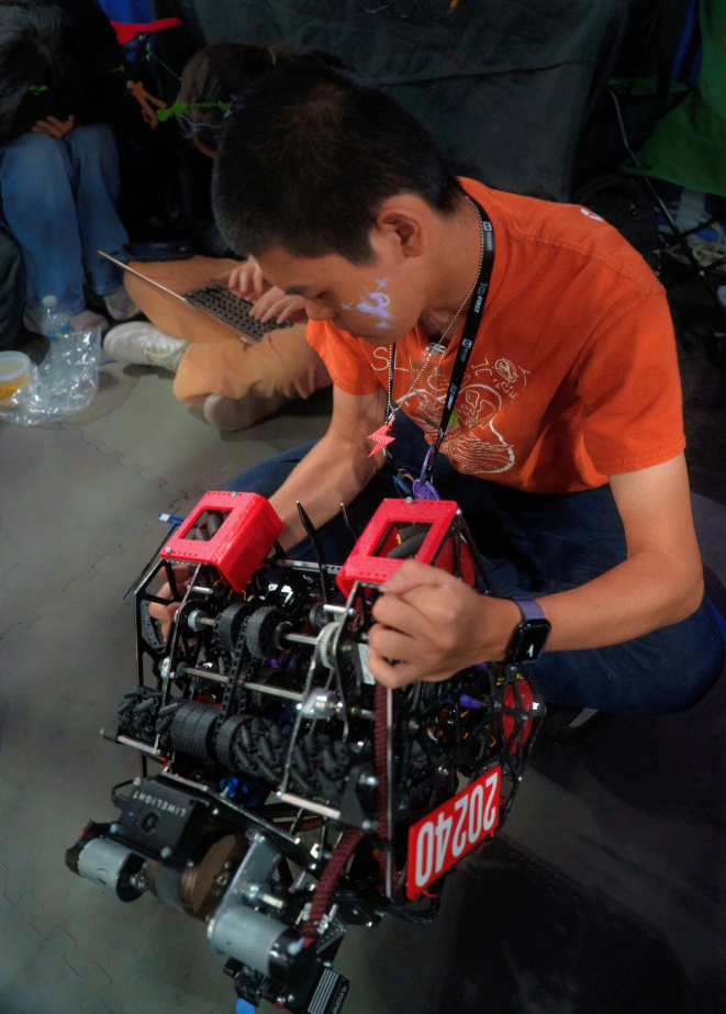 With a sigh, Jining Liu '26 inspects the robot carefully after it is brought back from a match. Liu, along with other hardware members, went through immense stress while trying to figure out what could be causing issues with robot performance. 